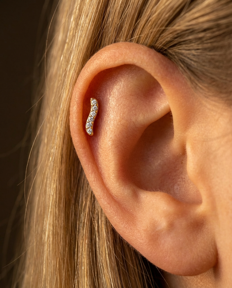 Elara bølge piercing med flat back i guld på øre